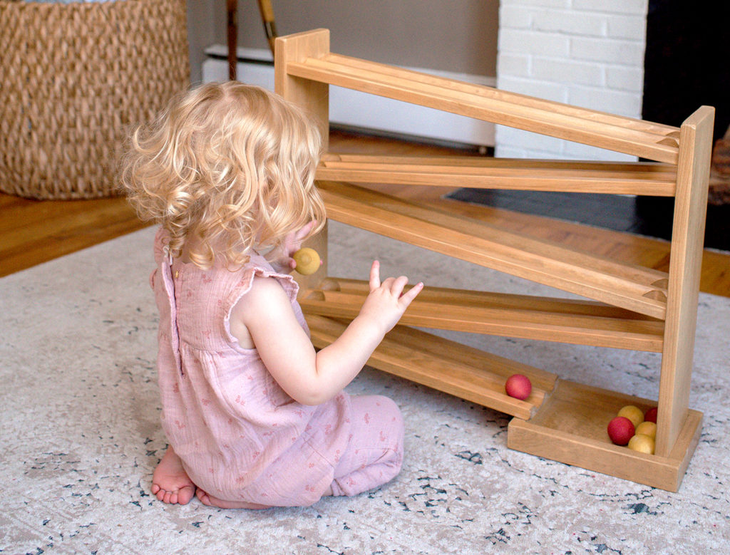 young girl playing with ball roller